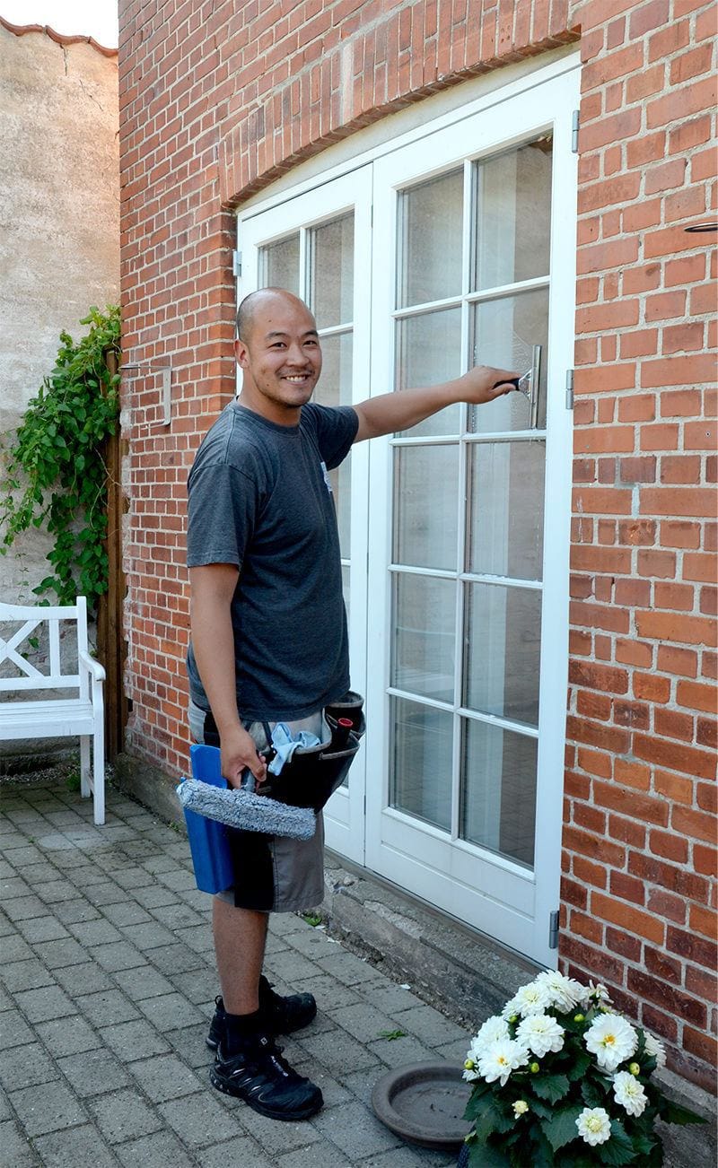 Mand pudser vinduer med svaber – effektiv vinduespudsning uden striber