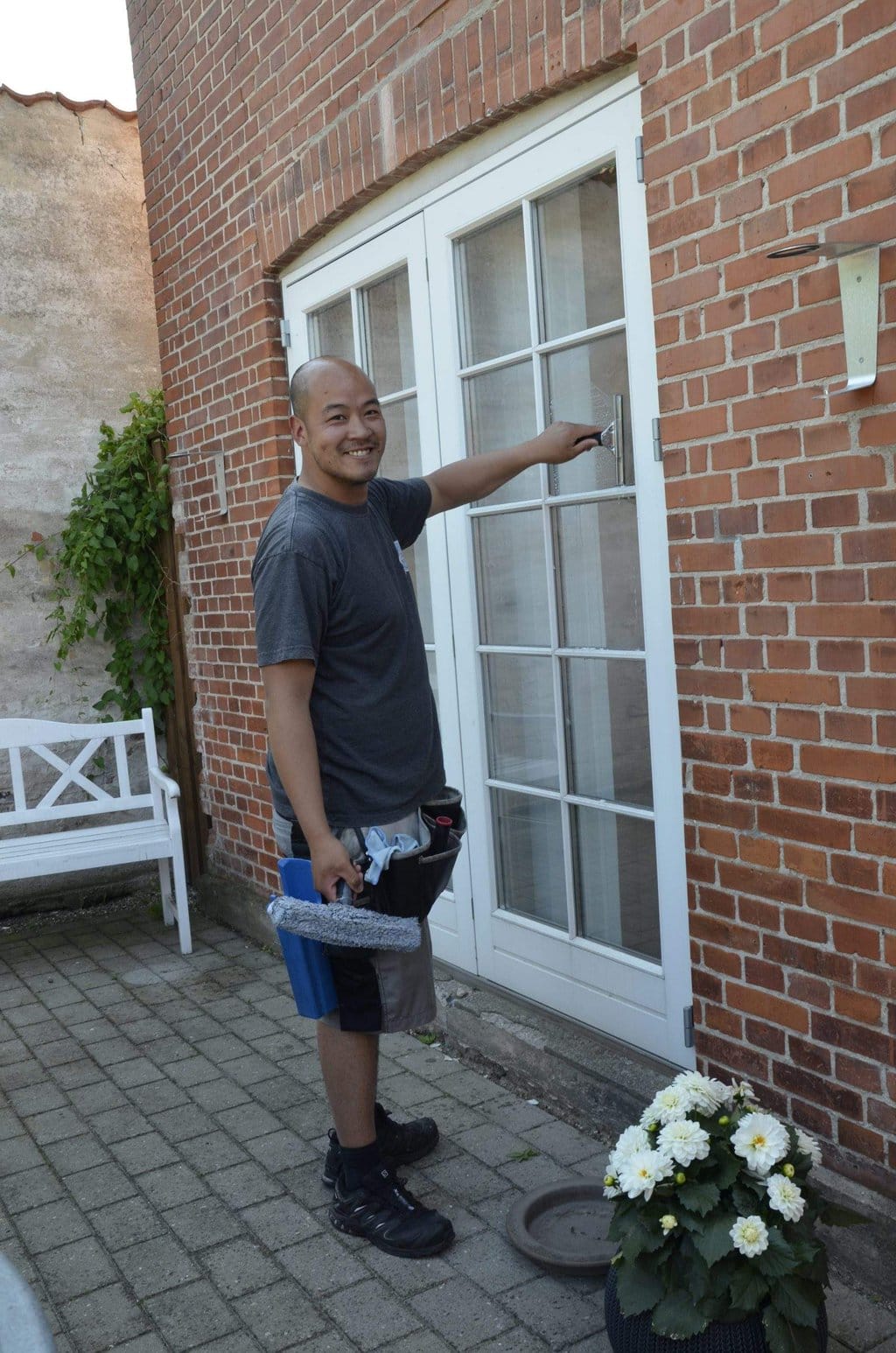 Vinduespolering Værløse står foran kundens vindue og er i gang med at give det en omgang vinduespolering 