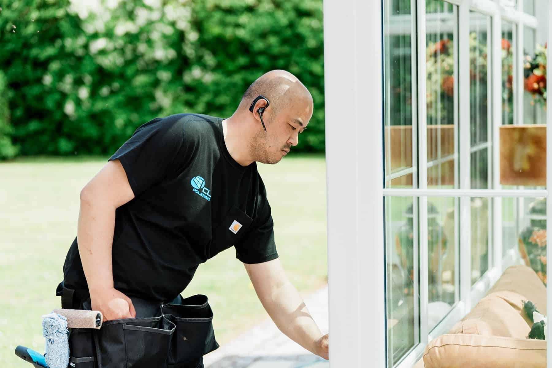 CL Polering pudser den nederste del af et vindue ved en bolig
